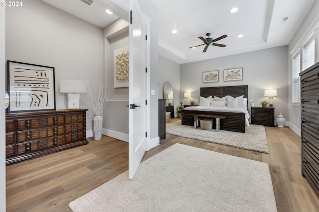 bedroom featuring wood-type flooring, a raised ceiling, and ceiling fan