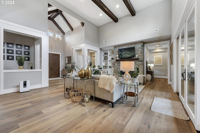 living room with high vaulted ceiling, built in features, light wood-type flooring, a fireplace, and beamed ceiling