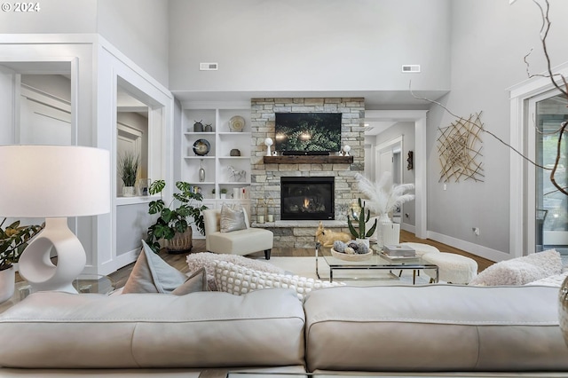 living room with a fireplace, built in features, hardwood / wood-style floors, and a high ceiling