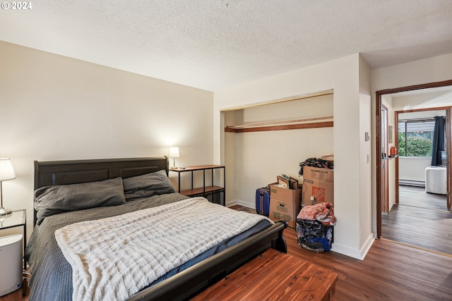 bedroom featuring a closet, a textured ceiling, and dark hardwood / wood-style floors