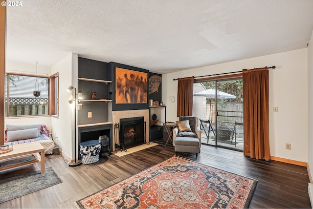 living room with a textured ceiling, a fireplace, and dark hardwood / wood-style floors