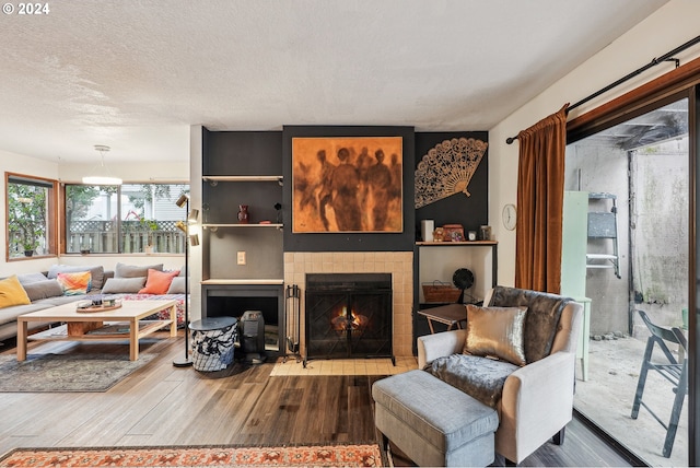 living room featuring hardwood / wood-style floors, a textured ceiling, and a tile fireplace