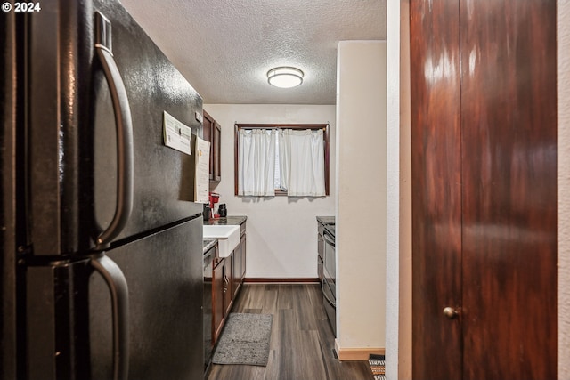 kitchen featuring dark wood-type flooring, black appliances, and a textured ceiling