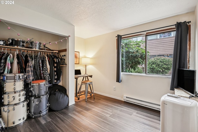 interior space with a closet, a textured ceiling, wood-type flooring, and a baseboard radiator