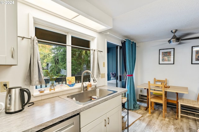 kitchen with ceiling fan, sink, light wood-type flooring, and white cabinets