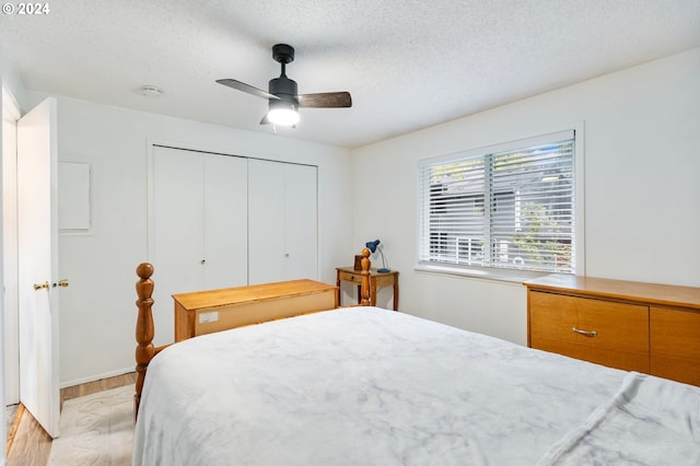 bedroom featuring a closet, a textured ceiling, light wood-type flooring, and ceiling fan