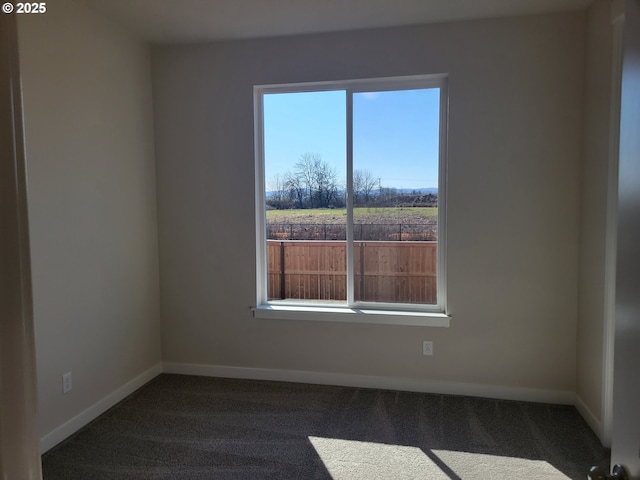 spare room with baseboards and dark carpet