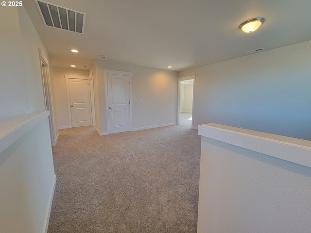 hallway featuring recessed lighting, visible vents, light carpet, and baseboards