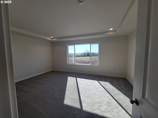 spare room with recessed lighting, dark carpet, a raised ceiling, and baseboards