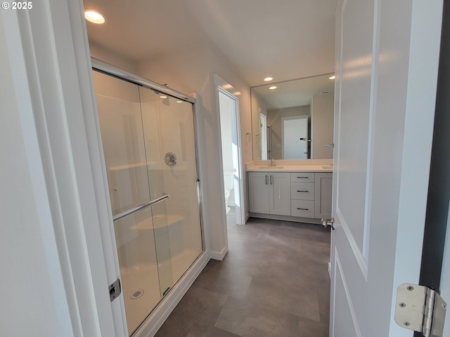 bathroom with toilet, a shower stall, vanity, and recessed lighting