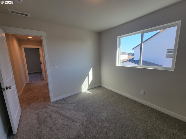 unfurnished room with carpet, visible vents, and baseboards