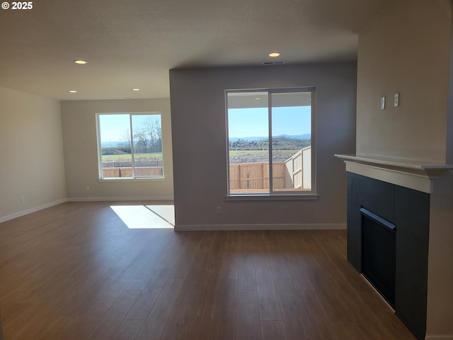 unfurnished living room featuring dark wood-style floors, plenty of natural light, and baseboards