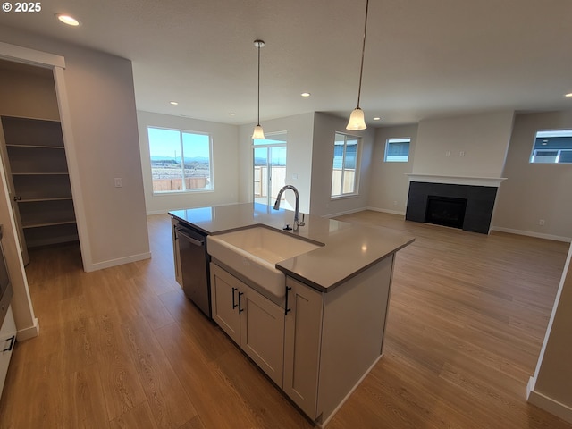 kitchen featuring recessed lighting, a fireplace, a sink, light wood-style floors, and stainless steel dishwasher