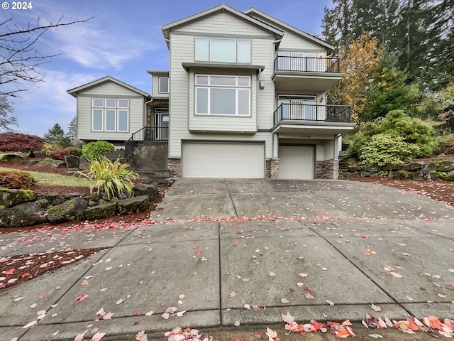 11574 SE Ross Rd, Happy Valley, OR 97086 - view of front of house with a balcony, a garage, concrete driveway, and stone siding