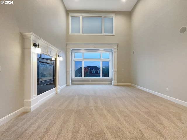 11574 SE Ross Rd, Happy Valley, OR 97086 - unfurnished living room with carpet flooring, a towering ceiling, baseboards, and a glass covered fireplace