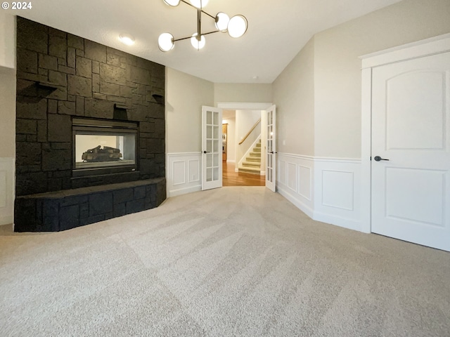 11574 SE Ross Rd, Happy Valley, OR 97086 - unfurnished living room featuring carpet flooring, a decorative wall, a wainscoted wall, a chandelier, and a stone fireplace