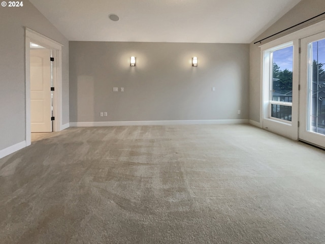 carpeted spare room with a wealth of natural light and vaulted ceiling