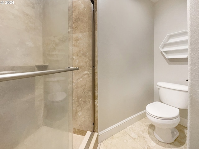 bathroom featuring tile patterned flooring, toilet, and a shower with shower door