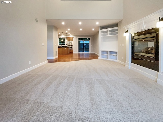 unfurnished living room featuring light carpet and built in features