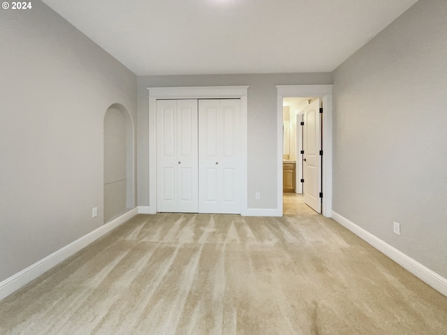 unfurnished bedroom with a closet and light colored carpet