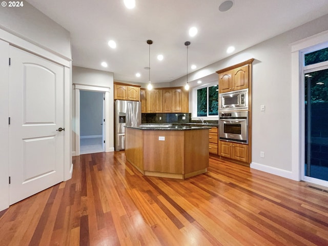 kitchen with pendant lighting, a center island, wood-type flooring, and appliances with stainless steel finishes