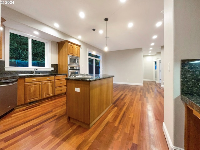 11574 SE Ross Rd, Happy Valley, OR 97086 - kitchen featuring appliances with stainless steel finishes, wood finished floors, a kitchen island, backsplash, and recessed lighting