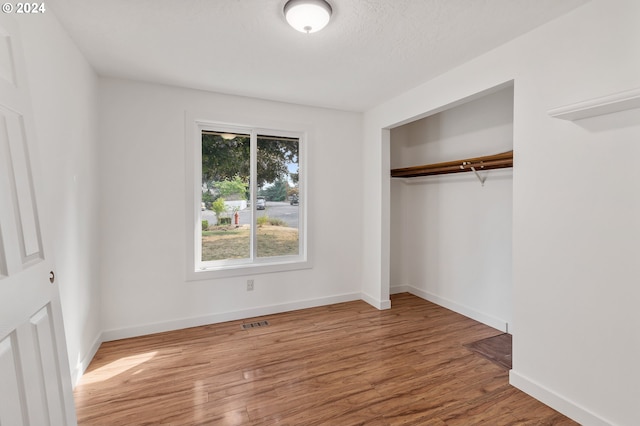 unfurnished bedroom featuring a closet, hardwood / wood-style floors, and a textured ceiling