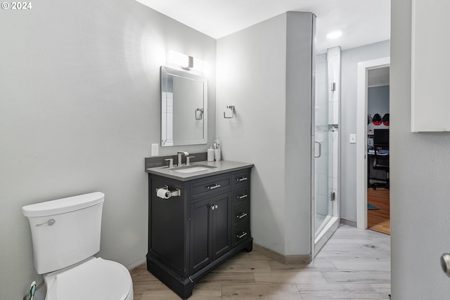 bathroom with a shower with door, vanity, toilet, and hardwood / wood-style floors