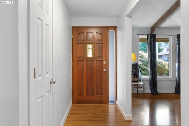 entryway with a textured ceiling, beamed ceiling, and hardwood / wood-style flooring