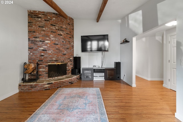 unfurnished living room with a fireplace, beamed ceiling, and light hardwood / wood-style flooring