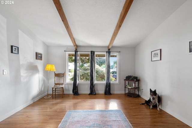 sitting room with a textured ceiling, beamed ceiling, and light hardwood / wood-style flooring