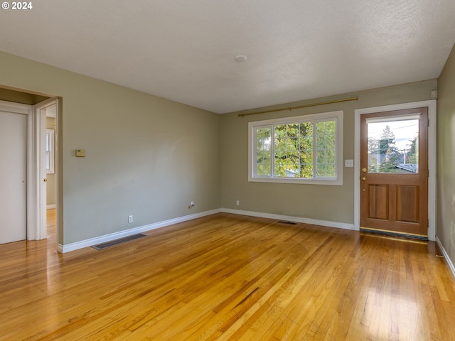 interior space with light hardwood / wood-style flooring, a textured ceiling, and a wealth of natural light