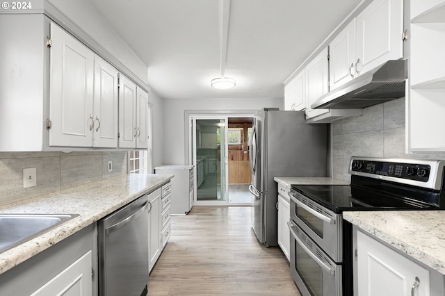 kitchen featuring stainless steel appliances, light hardwood / wood-style floors, backsplash, and white cabinetry