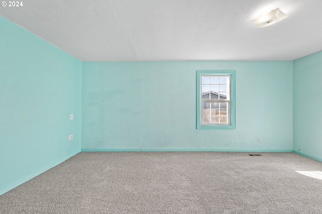 carpeted empty room with a textured ceiling