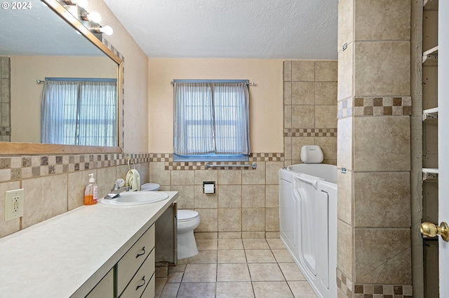 bathroom with washer and dryer, plenty of natural light, tile walls, and toilet