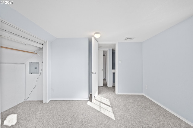 unfurnished bedroom featuring carpet floors, a closet, electric panel, and lofted ceiling