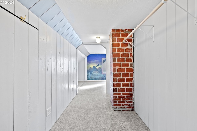 hall with vaulted ceiling, carpet, wooden walls, and a textured ceiling