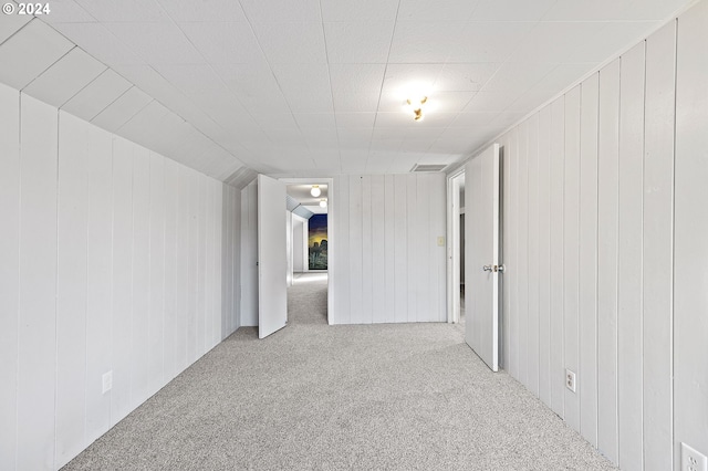 carpeted empty room with lofted ceiling and wood walls