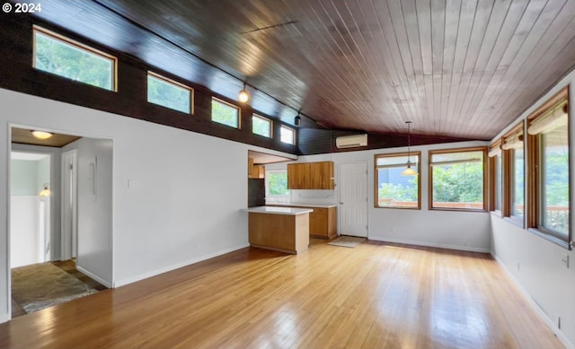 unfurnished living room with lofted ceiling, a wall unit AC, a healthy amount of sunlight, and light wood-type flooring