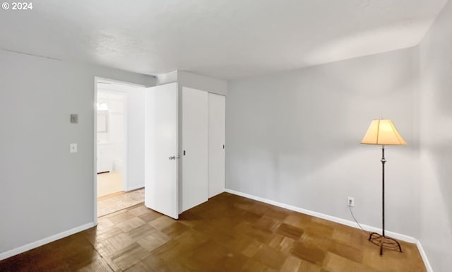 unfurnished bedroom featuring parquet floors and a closet