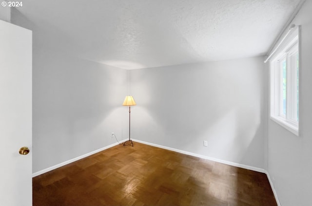 spare room with parquet flooring and a textured ceiling