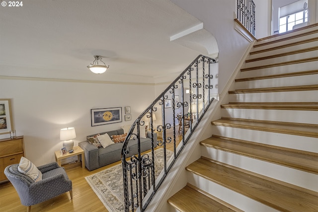 stairway featuring hardwood / wood-style flooring and ornamental molding