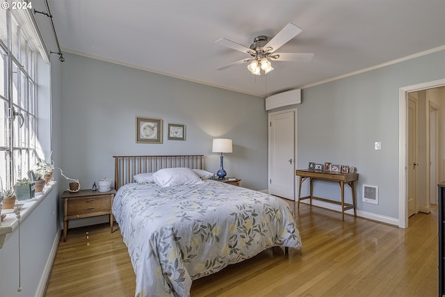 bedroom featuring ornamental molding, an AC wall unit, ceiling fan, and light hardwood / wood-style floors