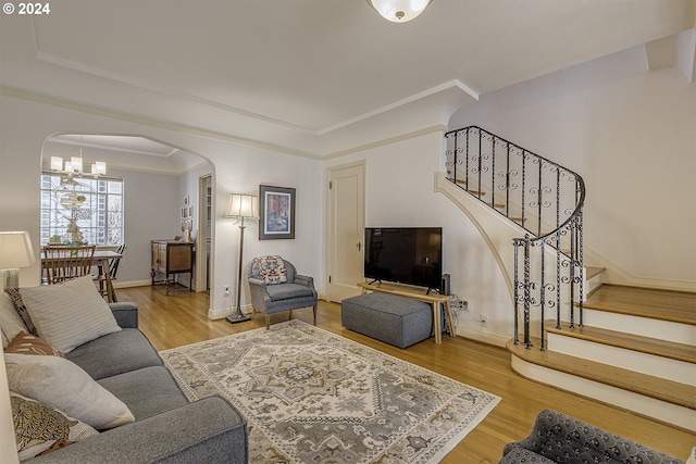 living room featuring an inviting chandelier, crown molding, wood-type flooring, and a tray ceiling