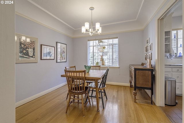 dining space with an inviting chandelier, crown molding, light hardwood / wood-style floors, and a tray ceiling