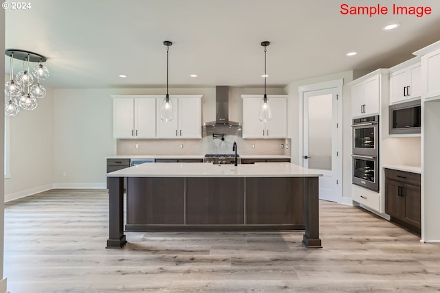 kitchen with light hardwood / wood-style floors, white cabinetry, and wall chimney range hood