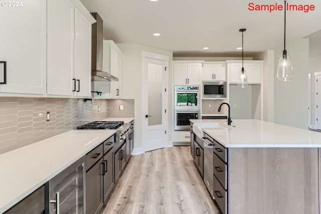 kitchen featuring decorative light fixtures, white cabinets, and wall chimney range hood