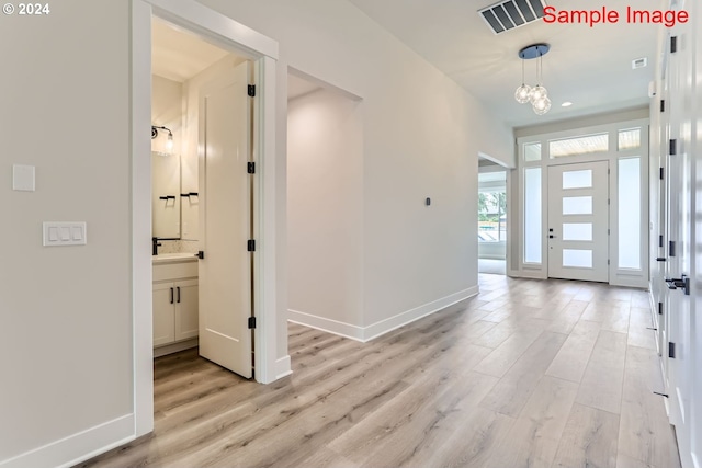 entrance foyer featuring a chandelier, sink, and light hardwood / wood-style floors