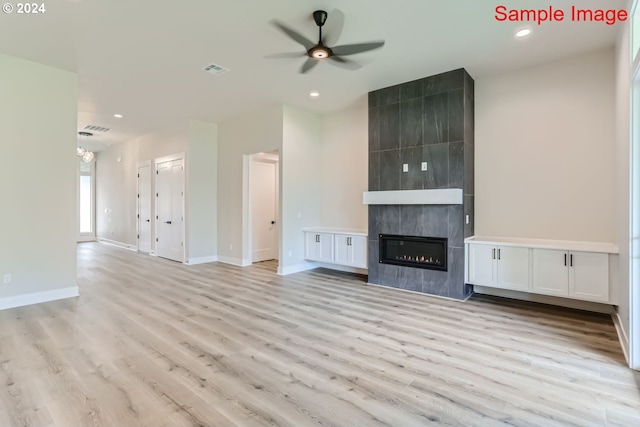 unfurnished living room featuring a tiled fireplace, ceiling fan, and light hardwood / wood-style floors