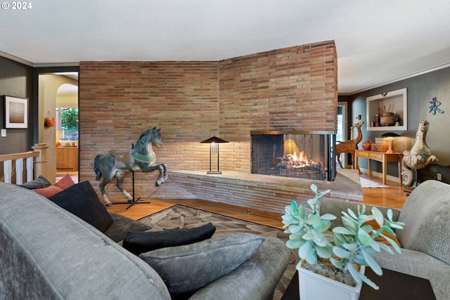 living room featuring hardwood / wood-style flooring, brick wall, a fireplace, and a textured ceiling